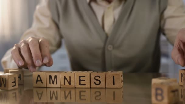 Idoso aposentado fazendo amnésia palavra de cubos de madeira na mesa, cuidados de saúde — Vídeo de Stock