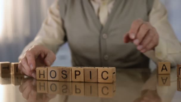 Abuelo haciendo palabra hospicio de cubos de madera en la mesa, cuidado de ancianos, trastorno — Vídeo de stock