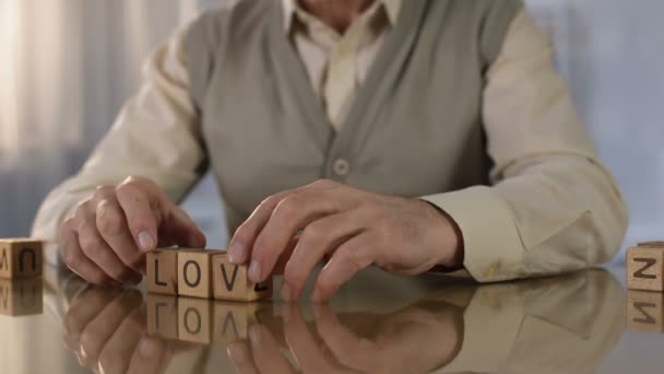 Homem sênior fazendo amor palavra de cubos de madeira na mesa, doença de memória, saúde — Vídeo de Stock