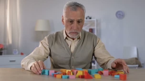 Больной пожилой человек смотрит на цветные кирпичики на столе, слабоумие старости — стоковое видео