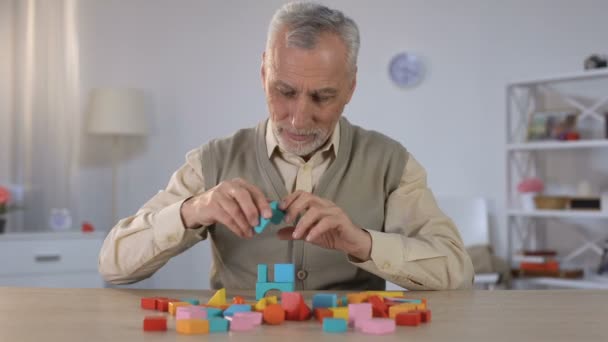 Viejo positivo jugando con cubos de madera, entrenamiento cognitivo en Alzheimer — Vídeos de Stock