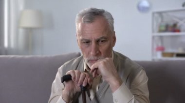 Yaşlı engelli adam kanepede oturan, ağır iç çekiyor, emeklilik yaşında hastalıklar