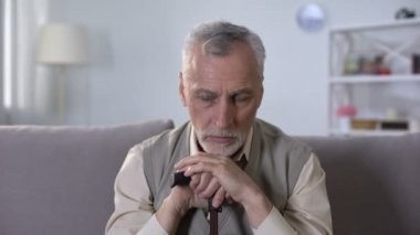 Depresif yaşlı adam sopa yaslanmış, ağır, yalnız ve yaşlılıkta hasta iç çekiyor