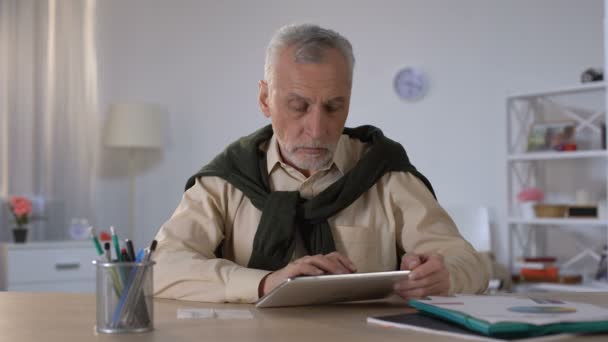 Старший человек, использующий планшет для оплаты кредитов и налогов в Интернете, банковские операции — стоковое видео
