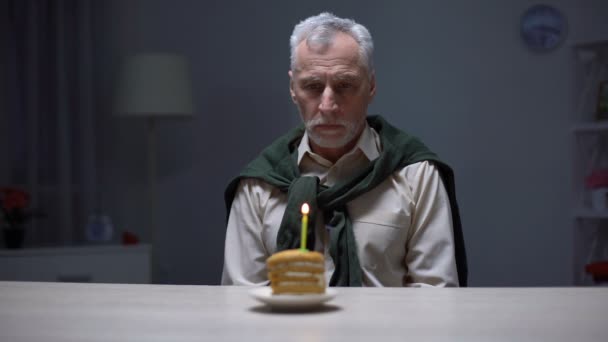 Uomo anziano depresso che guarda la torta di compleanno, festeggia la vacanza da solo a casa — Video Stock
