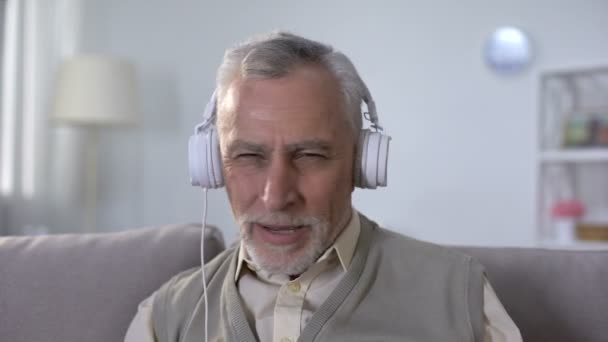 Hombre viejo positivo en auriculares escuchando canciones de rock, heavy metal desde la juventud — Vídeo de stock