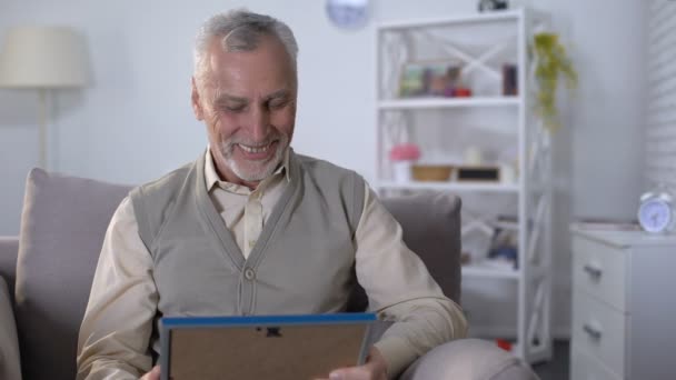 Großvater umarmt liebevoll Foto, erinnert sich an Wochenende mit Enkeln — Stockvideo