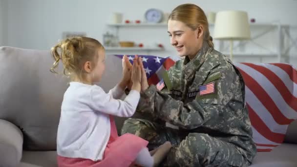 Happy american female soldier and child playing hands on sofa kid hugging mother — Stock Video
