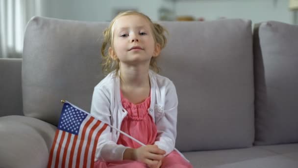Petite fille fière tenant le drapeau des États-Unis, reposant sur le canapé à la maison, jour de l'indépendance — Video