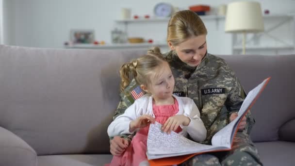 Vrouwelijke soldaat en schattige dochter kijken naar Foto's in kleurboek vrije tijd — Stockvideo