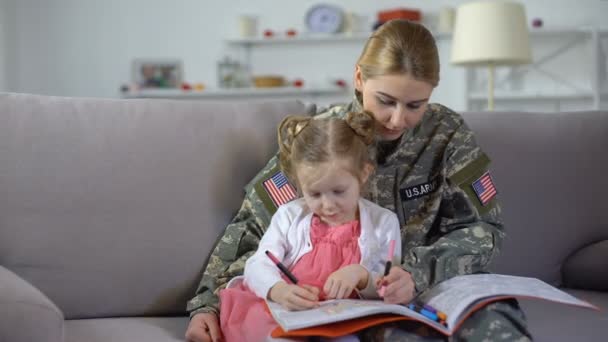 Madre en uniforme militar dibujo en libro para colorear juntos, tiempo libre en casa — Vídeo de stock