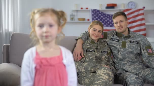 Padres alegres en uniforme militar de los E.E.U.U. que admiran a hija pequeña que mira cámara — Vídeo de stock