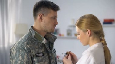 Üzgün kadın erkek asker üzerinde ahşap haç kolye giyen ve sarılma, veda