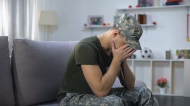 Sinirli erkek askeri elleri ile yüz kapanış, evde kanepede oturan, Ptsd