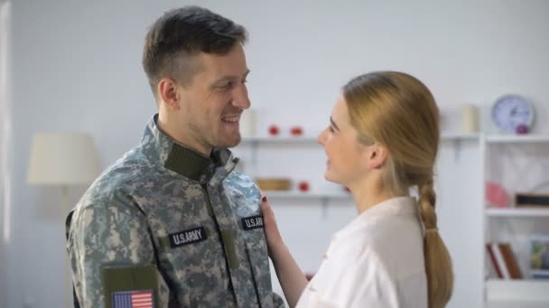 Заботливая женщина регулирует форму американского солдата бойфренд, обнимая со всей любовью — стоковое видео