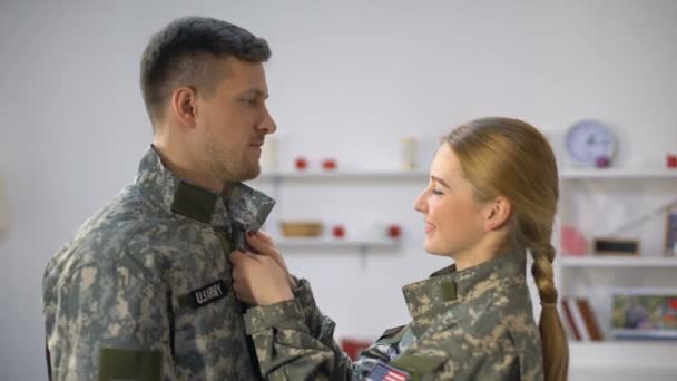 Lachende Amerikaanse soldaat vrouwelijke aanpassen uniforme militaire vriendje, liefdevolle paar — Stockvideo