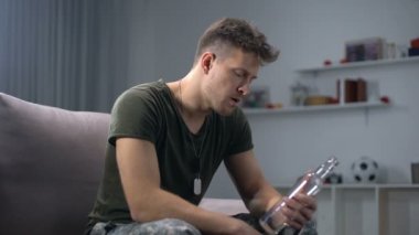 Üzgün erkek asker evde şişelenmiş alkollü içecek içiyor, Ptsd acı
