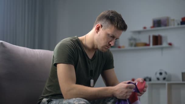 Soldado estadounidense sentado en un sofá y besando bandera nacional, patriotismo y orgullo — Vídeo de stock