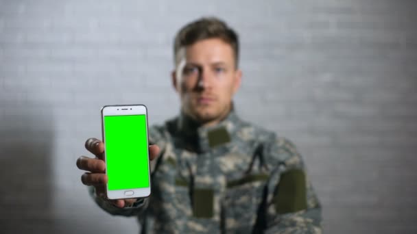 Soldat masculin en uniforme montrant smartphone avec écran vert à la caméra, app — Video