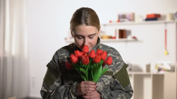 Joyeux soldat féminin en uniforme sentant l'arôme de bouquet de tulipes et souriant — Video