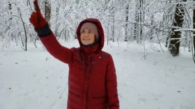 Kış ormanında dallara dokunan mutlu kadın, doğanın tadını çıkarıyor, gezinti