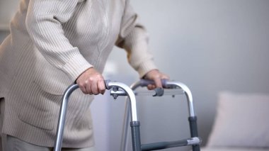 Yürüme çerçevesi kullanan yaşlı kadın, eklem travması sonrası rehabilitasyon, yakın çekim