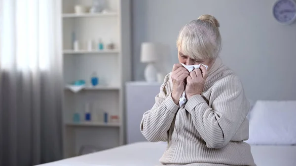 Depressed elderly woman deeply crying in rehabilitation center, health problem