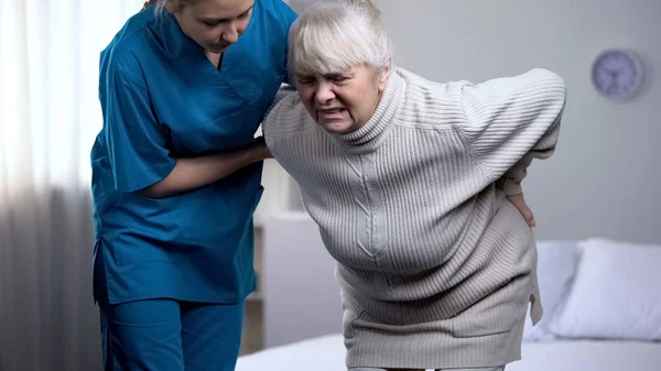 看護師の医療センター 腰の痛みから苦しんでいる老婦人の世話 — ストック写真