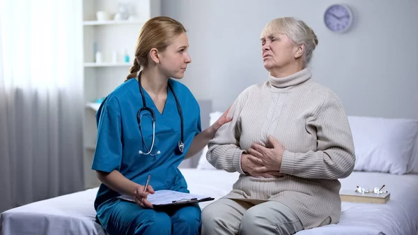 Doktor Podporuje Staršího Pacienta Píše Diagnózu Lékařských Záznamech Bolesti — Stock fotografie