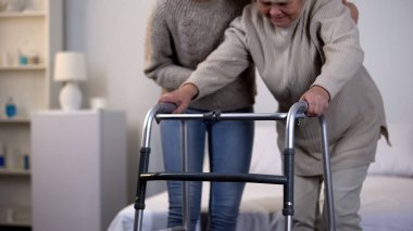 Yaşlı kadın yürüyen çerçeve, travma sonrası rehabilitasyon kullanarak yardım gönüllü