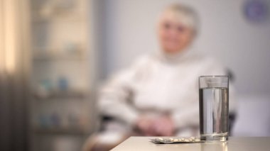 Masada beyaz hap ve su bardağı, tıbbi reçete, vitamin takviyeleri.