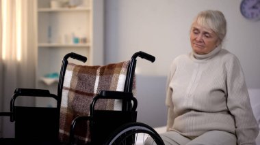 Tekerlekli sandalyede Rehabilitasyon Merkezi yakınındaki kanepede oturan yaşlı kadın üzgün