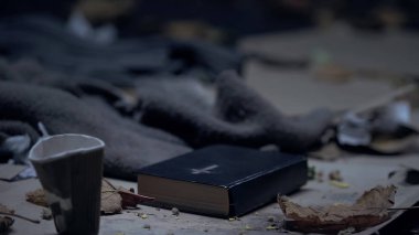 İncil ve çöp ile yerde kağıt bardak, evsiz insanlar için dua, umut