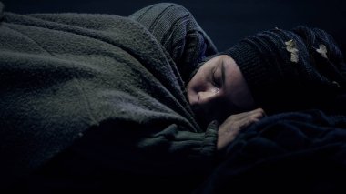 Crying homeless person covered by blanket sleeping on city street, problems clipart