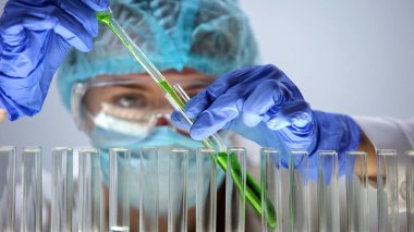 Test tüpüne, organik ürünler yeşil sıvı dökme laboratuvar asistanı
