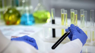 Biyolojik araştırmacı tüp siyah sıvı bakarak, petrol üretim endüstrisi