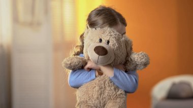 Preschool shy girl hiding behind teddy bear, childish psychological problems clipart