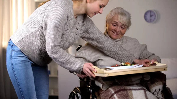 障害を持つ老婦人に夕食を提供する女性ボランティア 高齢者介護 — ストック写真