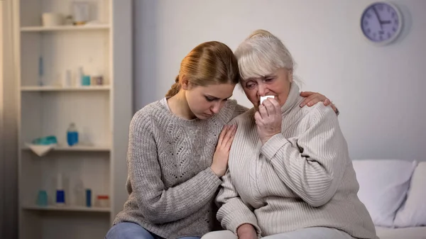 Granddaughter hugging and supporting crying grandmother, incurable disease