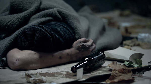 Drunk homeless person sleeping on city street, alcohol abuse, social problem