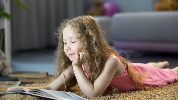Симпатична Маленька Дівчинка Читає Пригодницьку Книгу Лежить Підлозі Проводячи Дозвілля — стокове фото