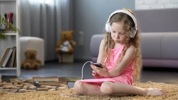 孩子在耳机听音乐在智能手机 沉迷于技术 — 图库照片