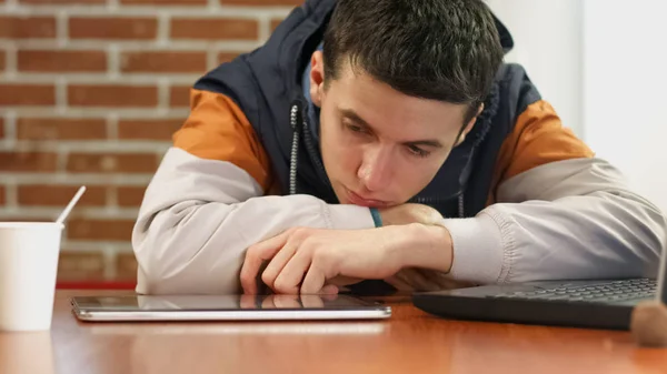 Набридлий Студент Читає Новинний Планшет Молодий Чоловік Сидить Сам Кафе — стокове фото