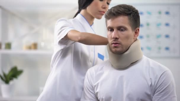 Uważny chirurg mocowanie męskiej pianki pacjenta kołnierz szyjki macicy po urazie, Rehab — Wideo stockowe