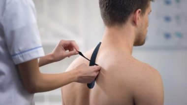 Hasta üst sırtında Y şekilli bantlar uygulayarak deneyimli Doktor, sağlık