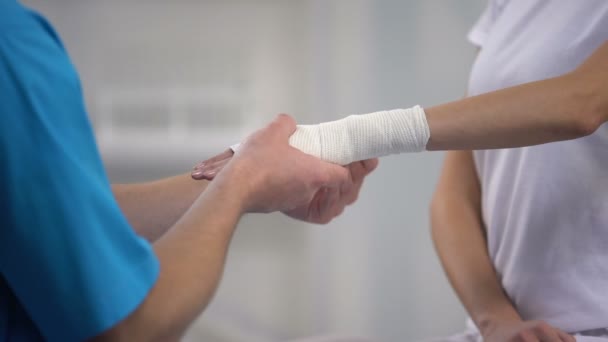 Ortopedista aplicando envoltura elástica de muñeca en dislocación de la articulación de la mano del paciente femenino — Vídeo de stock