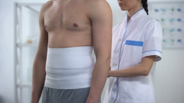 Női orvos alkalmazó vissza wrap férfi beteg csökkenti hipoxiás szöveti sérülés — Stock videók