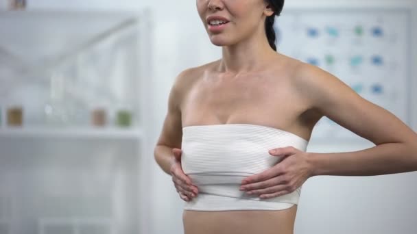 Woman in elasto-fit breast compression touching wrap, feeling pain after surgery — Stock Video