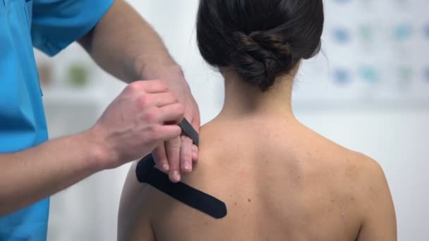 Fisioterapista che applica nastri a forma di Y sulla tensione muscolare della spalla del paziente femminile — Video Stock