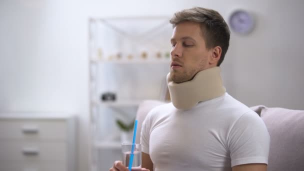 Man in foam cervical collar trying to drink glass water with straw, poor attempt — Stock Footage Man in foam cervical collar trying to drink glass water with straw, poor attempt Royalty Free Stock Footage